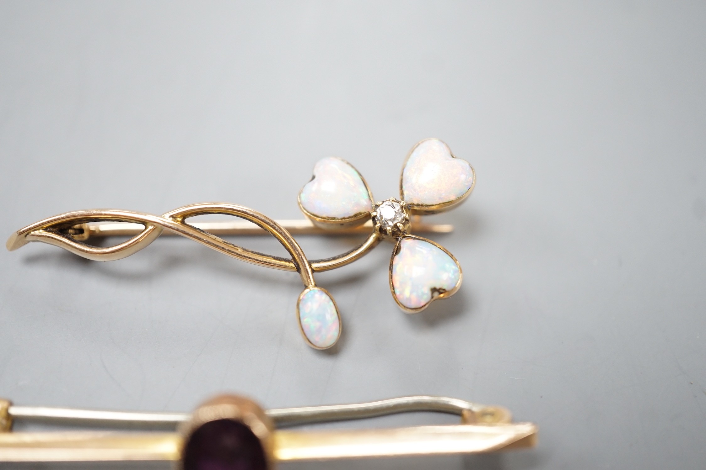A yellow metal, four stone white opal including heart shape and diamond set foliate brooch, 40mm and a yellow metal and oval cut garnet set bar brooch, gross weight 5.4 grams.